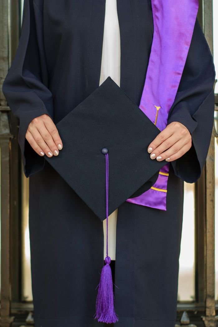 Study Abroad Close-up of a graduate holding a cap, symbolizing academic achievement at a ceremony.