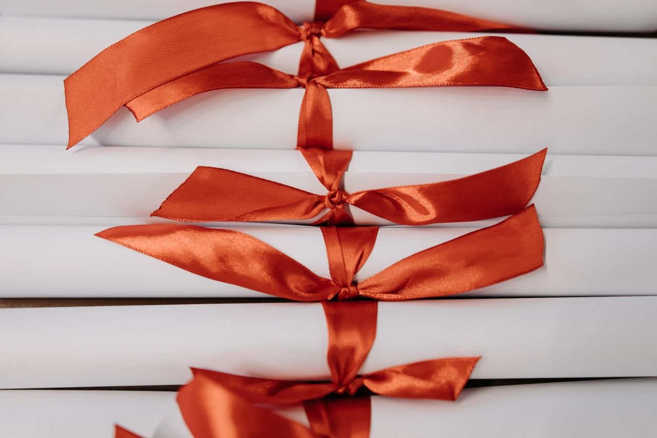 Home Close-up of graduation diplomas tied with vibrant red ribbons, symbolizing achievement and success.