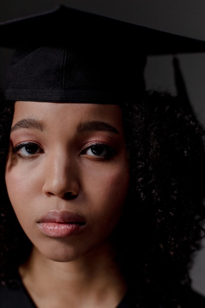 Home Close-up portrait of a young black female graduate wearing a cap, celebrating her achievement.